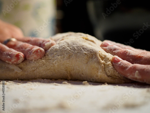 hands of a young woman with a bread dough in a white table