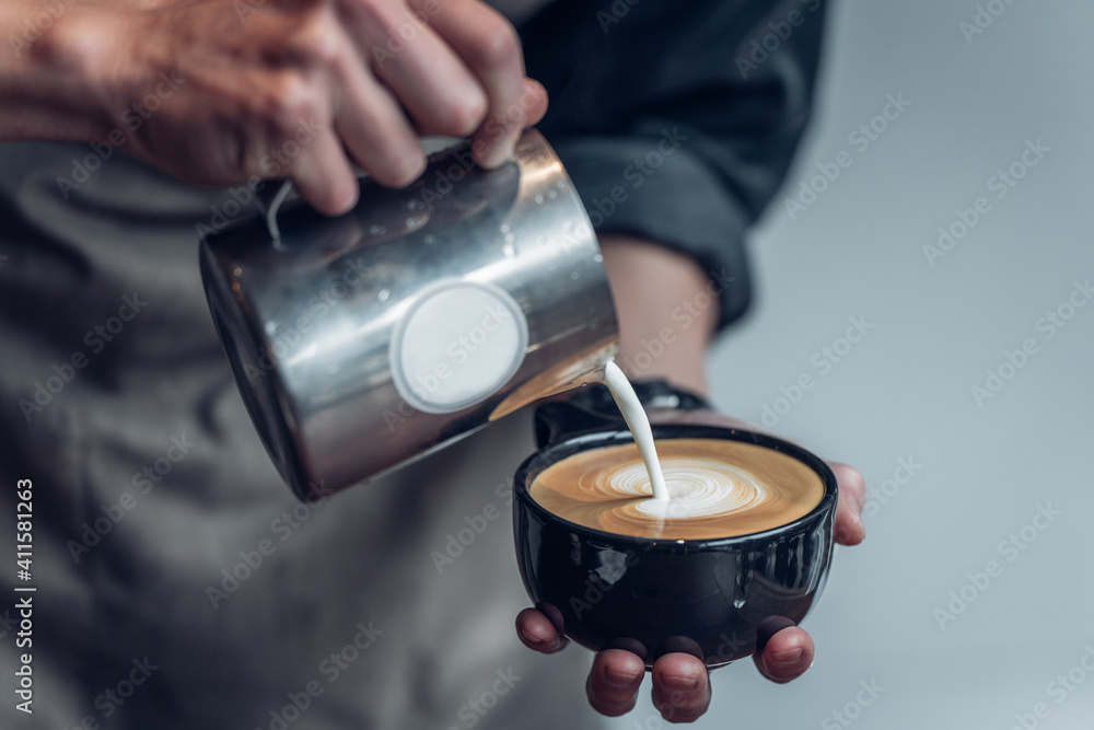 The barista pouring steam milk into the espresso coffee to make the pattern on top as the latte art. The barista pouring steam milk into the espresso coffee to make the pattern on top as the latte art.