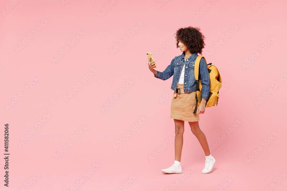 Full length happy smart smiling little african american kid school girl 12-13 year old in casual denim clothes backpack hold hands back of head isolated on pink background Childhood education concept - obrazy, fototapety, plakaty 