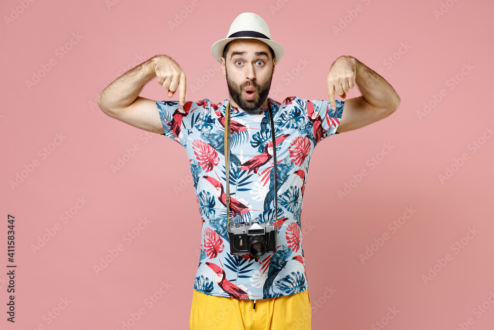 Shocked young traveler tourist man in summer clothes hat with photo camera pointing index fingers down isolated on pink background. Passenger traveling abroad on weekends. Air flight journey concept. Shocked young traveler tourist man in summer clothes hat with photo camera pointing index fingers down isolated on pink background. Passenger traveling abroad on weekends. Air flight journey concept.