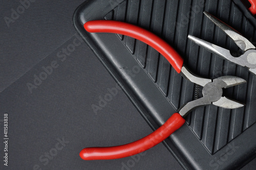 small pliers and pliers lie on a closed toolbox. view from above.