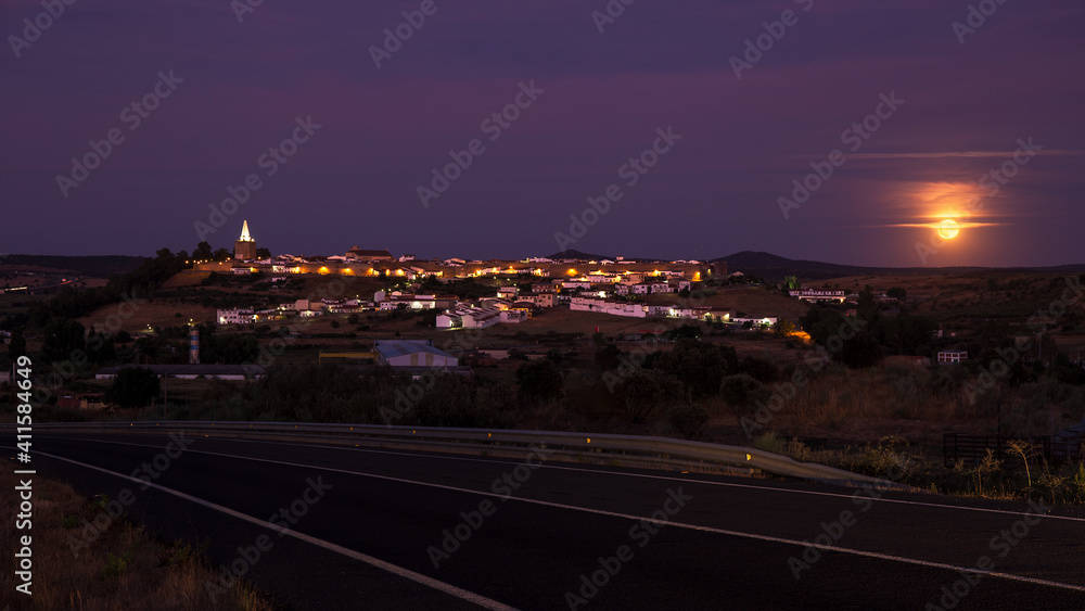 Night landscape of town with moon and road in the foreground