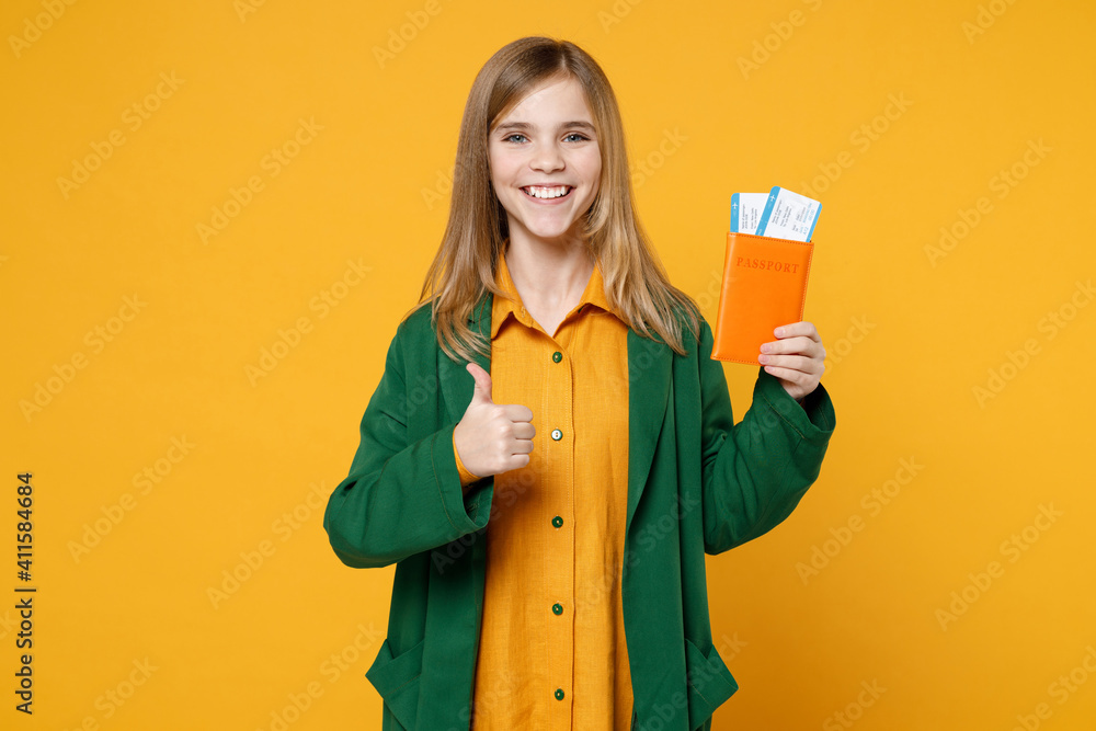 Traveler tourist little happy kid girl in casual clothes hold passport tickets show thumb up gesture isolated on yellow background Passenger travel abroad weekends getaway. Air flight journey concept. Traveler tourist little happy kid girl in casual clothes hold passport tickets show thumb up gesture isolated on yellow background Passenger travel abroad weekends getaway. Air flight journey concept.