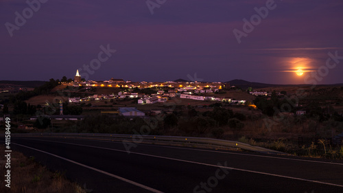 Night landscape of town with moon and road in the foreground