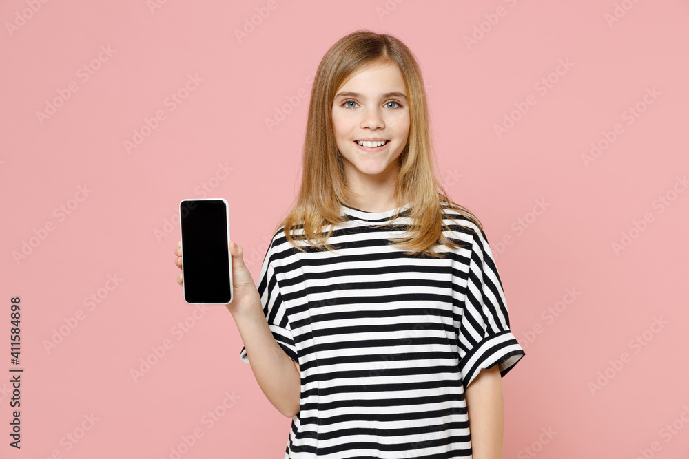 Little blonde smiling kid girl 12-13 years old in striped oversized t-shirt hold mobile phone with blank screen workspace area isolated on pastel pink background children. Childhood lifestyle concept. Little blonde smiling kid girl 12-13 years old in striped oversized t-shirt hold mobile phone with blank screen workspace area isolated on pastel pink background children. Childhood lifestyle concept.