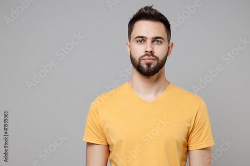 Canvas Print Young caucasian european serious bearded attractive handsome student man 20s wear casual yellow basic t-shirt looking camera isolated on grey color background studio portrait People lifestyle concept