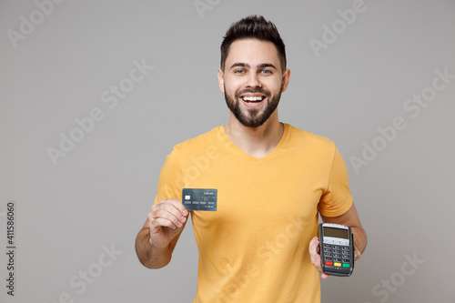 Fotografie Young caucasian smiling bearded man in casual yellow basic t-shirt hold wireless