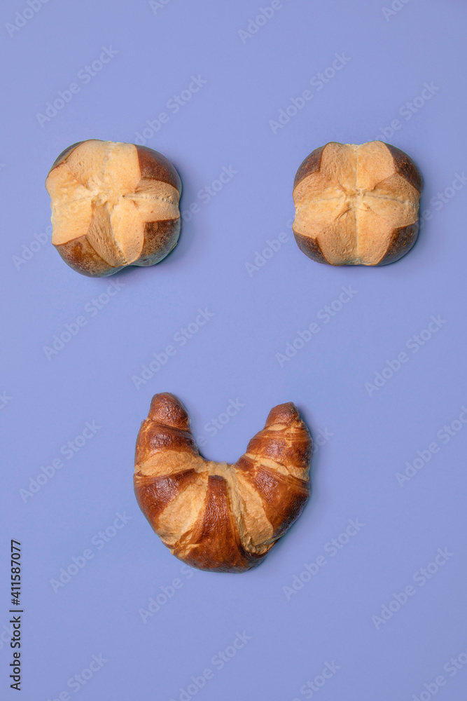 Smile face from croissant and danish pastries. Simple flat lay concept with purple background, bakary Smile face from croissant and danish pastries. Simple flat lay concept with purple background, bakary