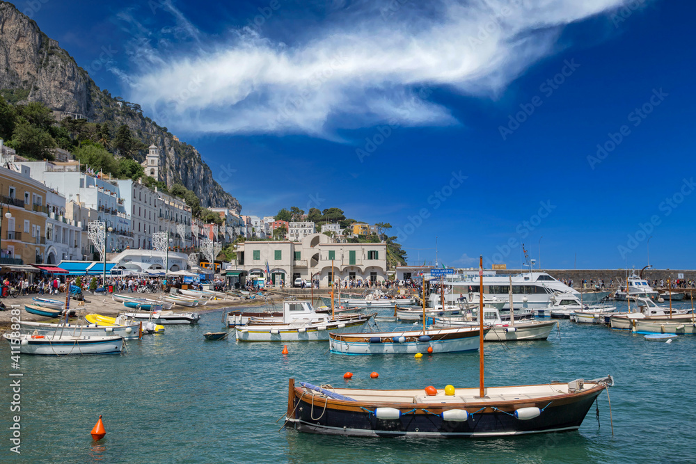 Marina with yachts and boats at Capri Island town. View of boat harbor and Marina Grande, on the Island of Capri, with colorful buildings and high mountains in the background, Tyrrhenian sea, Italy