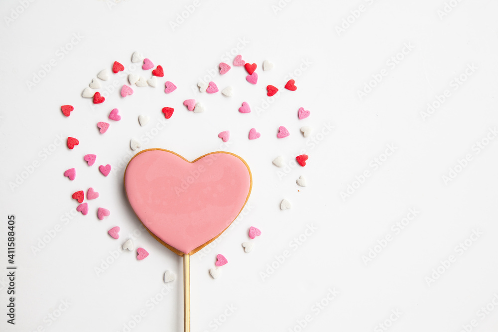 One Big sweet heart on a stick and lots of little hearts around it on a white background. Pink cookies for Valentine's Day