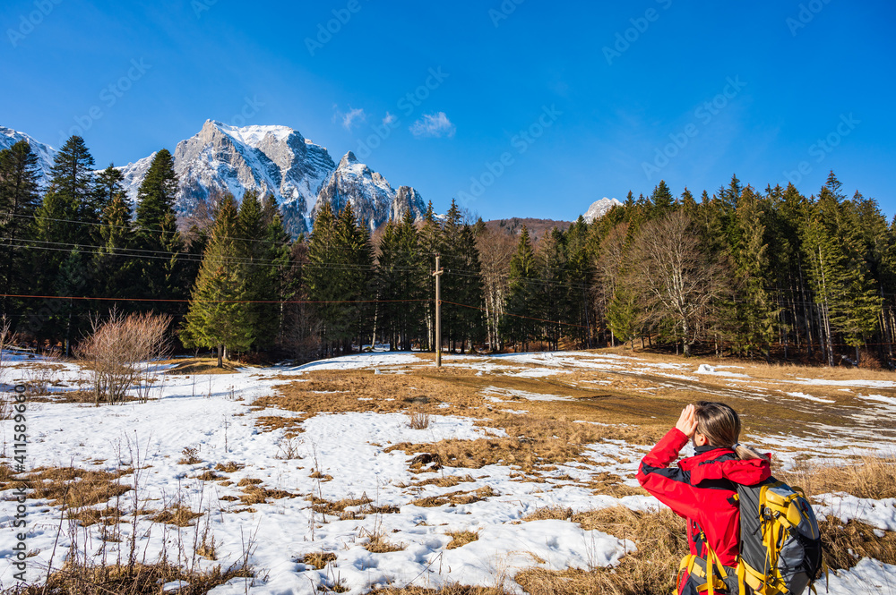 Female hiker looking up to high rising mountain range in Romanian Carpathians