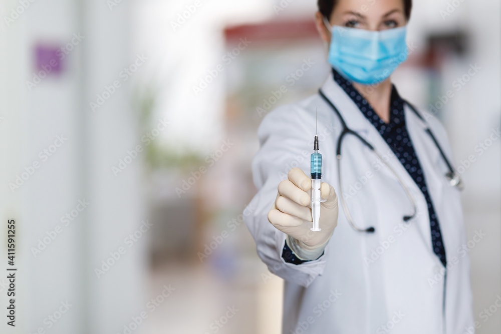 Doctor shows syringe with vaccine on blurred background. Doctor shows syringe with vaccine on blurred background.