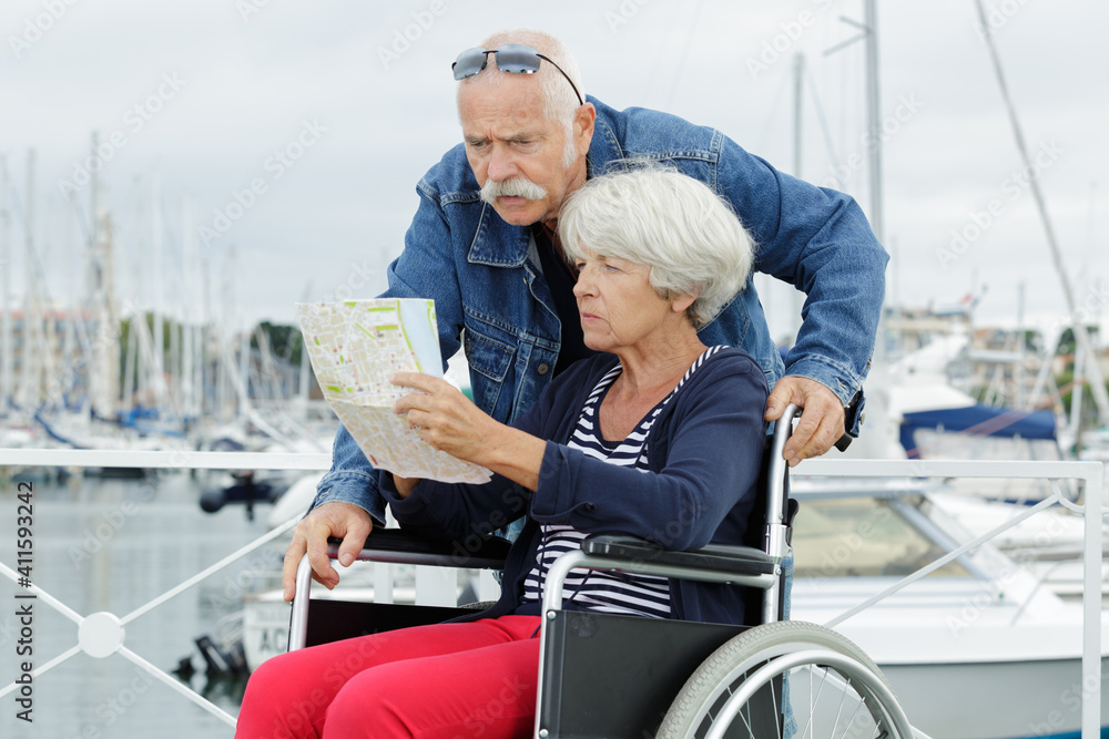 handicapped woman in wheelchair with husband looking at a map handicapped woman in wheelchair with husband looking at a map