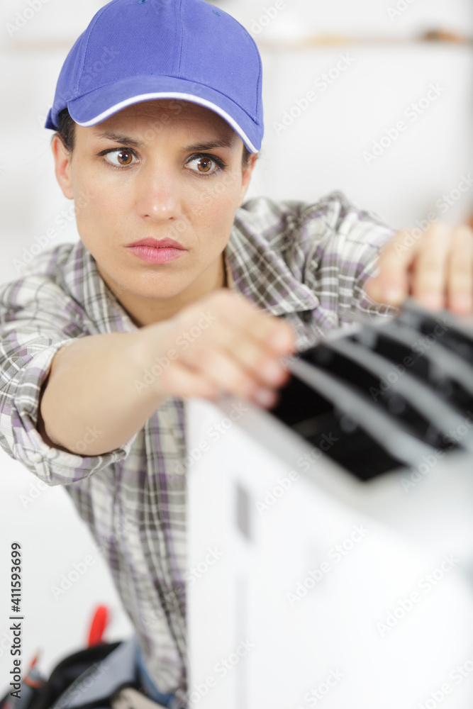 young woman adjusts the temperature of the air conditioner young woman adjusts the temperature of the air conditioner