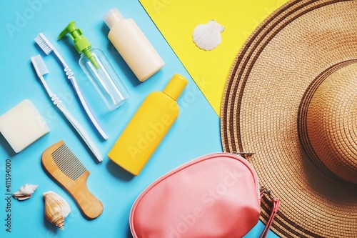 Luggage and summer travel accessories bag, toiletries kit. Flat lay composition object photography. Soap bar, toothbrushes, empty bottles for cosmetics, sunscreen cream, bag and hat photo