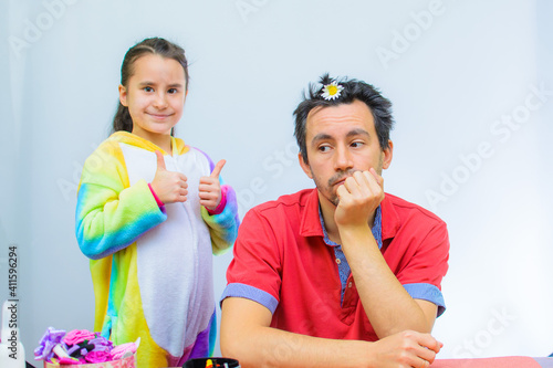 Little girl plays with her father at home in a beauty salon, combing her hair