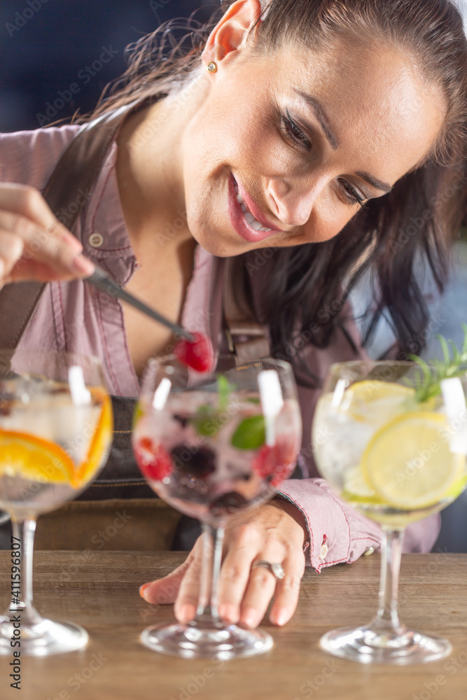 Detail of a barmaid doing finishing touches of cocktail decoration in a bar Detail of a barmaid doing finishing touches of cocktail decoration in a bar