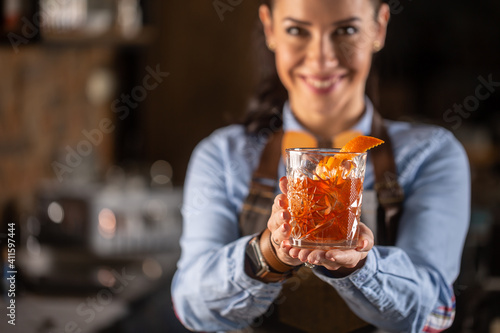 Old fashioned drink in ornamental glass offered by a female bartender in a pub