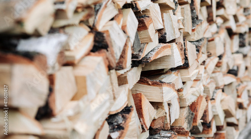 Chopped birch firewood stacked in a woodpile. Raw materials, fuel for heating houses and wood-fired boilers. Side view with shallow depth of field. Firewood background image