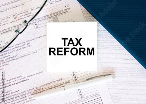 Tax form with business card with text Tax Reform. Notepad, eyeglasses and white pen