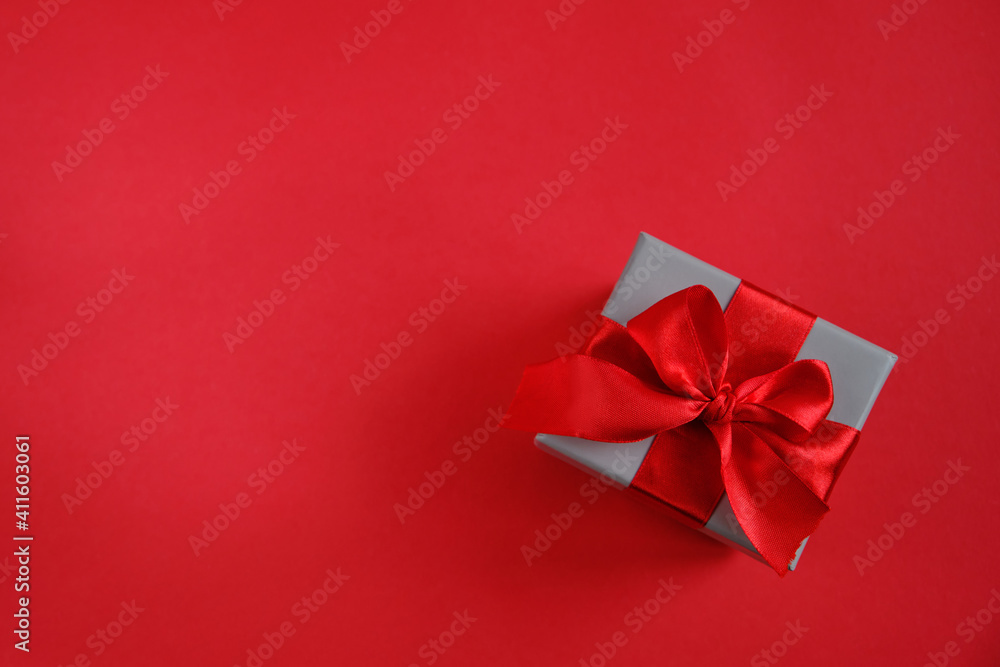 Small gift box with red ribbon on red background