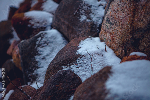 Close-up of large cobblestones and rocks on the river bank covered with snow in winter
