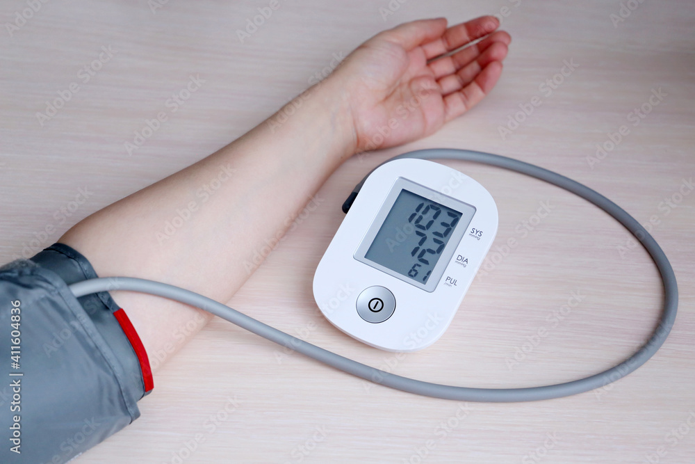 Woman measuring blood pressure with electronic digital tonometer, female hand close up. Arterial hypotension and cardiology concept Woman measuring blood pressure with electronic digital tonometer, female hand close up. Arterial hypotension and cardiology concept