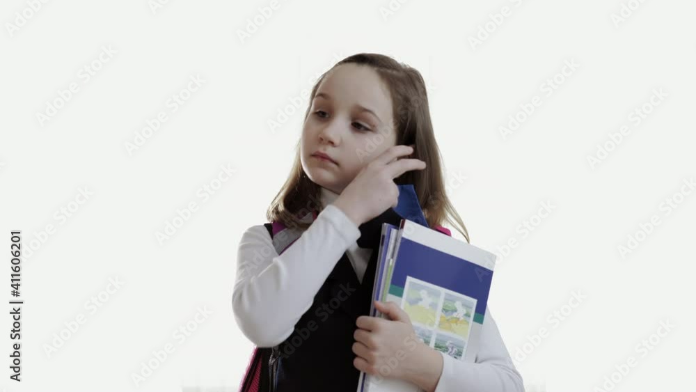 the schoolgirl with a backpack and books in her hands takes off her mask and takes a deep breath on a white background. High quality 4k footage the schoolgirl with a backpack and books in her hands takes off her mask and takes a deep breath on a white background. High quality 4k footage