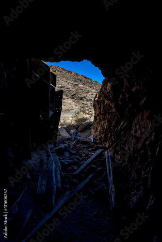 Looking out of a mine shaft filled with leftover mining equipment and garbage into the daylight