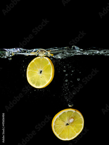 sliced lemon falling in the water on dark background. Underwater view. Cooking, vegetarian, cooking at home concept