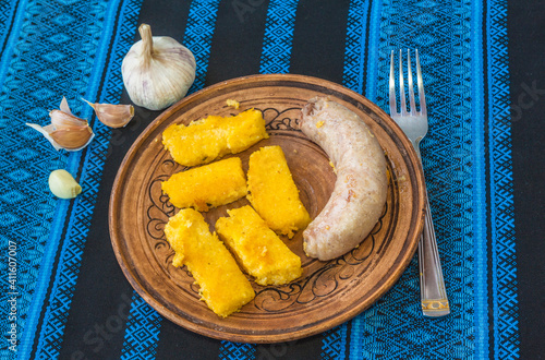 Mamalyga  and  homemade sausage, head of garlic on a plate photo