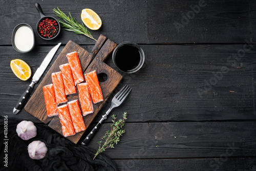 Fresh Crab meat stick surimi , on wooden cutting board, on black wooden table background, top view flat lay  , with copyspace  and space for text photo
