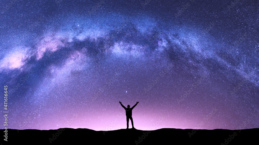 Arched Milky Way and happy man at night. Silhouette of guy with raised up arm on the hill, purple sky with stars, pink light in summer. Galaxy. Space background. Landscape with milky way arch. Travel Arched Milky Way and happy man at night. Silhouette of guy with raised up arm on the hill, purple sky with stars, pink light in summer. Galaxy. Space background. Landscape with milky way arch. Travel