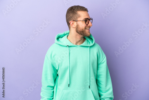 Young handsome caucasian man isolated on purple background looking side © luismolinero