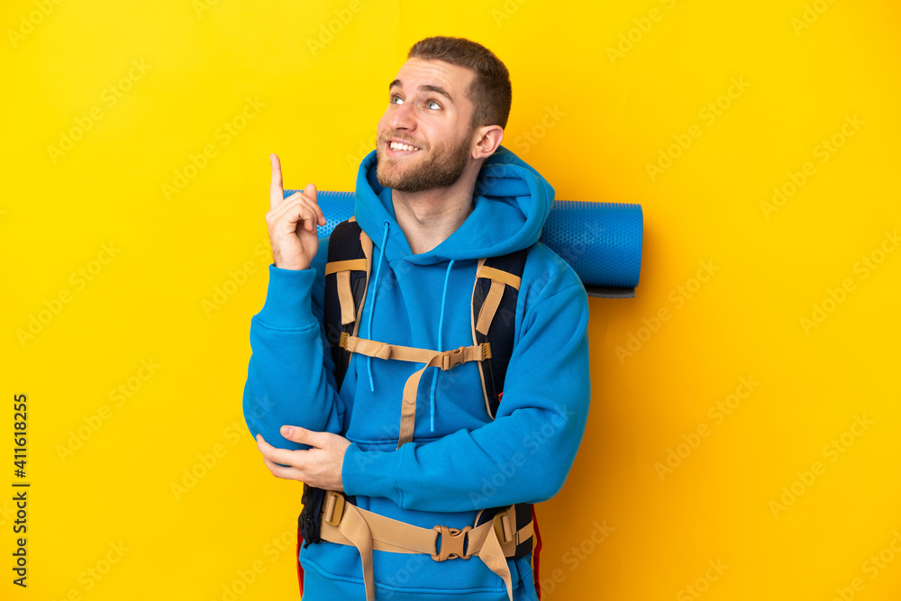 Young caucasian mountaineer man with a big backpack isolated on yellow background pointing up a great idea Young caucasian mountaineer man with a big backpack isolated on yellow background pointing up a great idea