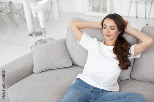 Pretty smiling authentic woman relaxing on couch in living room. Nice weekend.