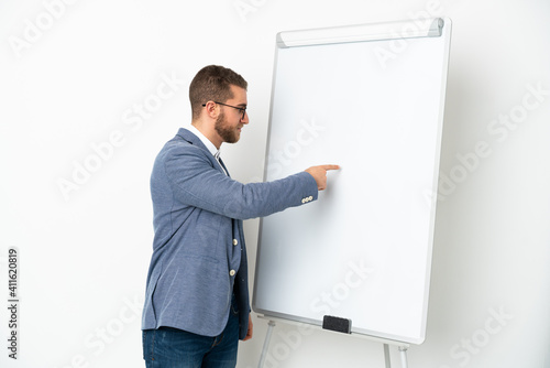 Young handsome caucasian man isolated on white background giving a presentation on white board © luismolinero