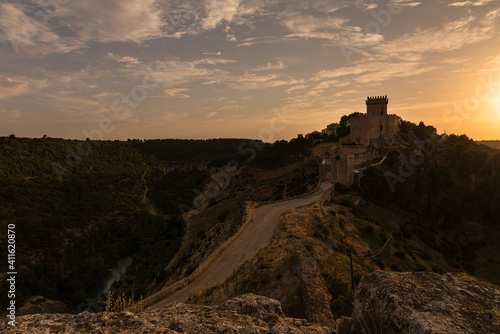 Landscape with a road toward the fortified city of Alarcon with the castle on top of the hill at sunset, Cuenca, Spain