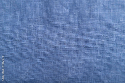 Fragment of smooth blue linen tissue. Top view, natural textile background.