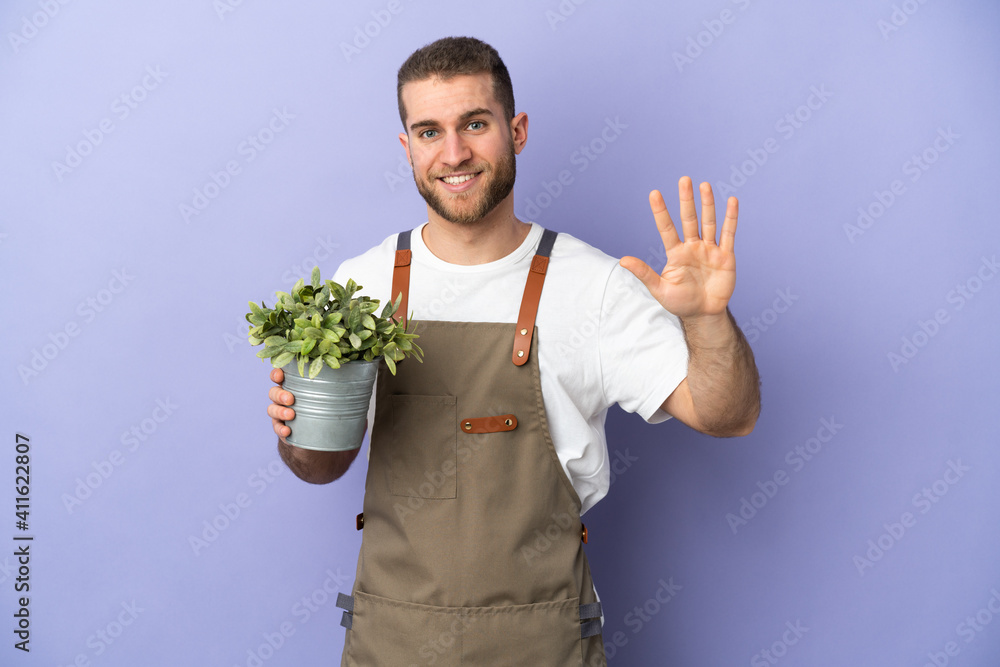 Gardener caucasian man holding a plant isolated on yellow background counting five with fingers Gardener caucasian man holding a plant isolated on yellow background counting five with fingers
