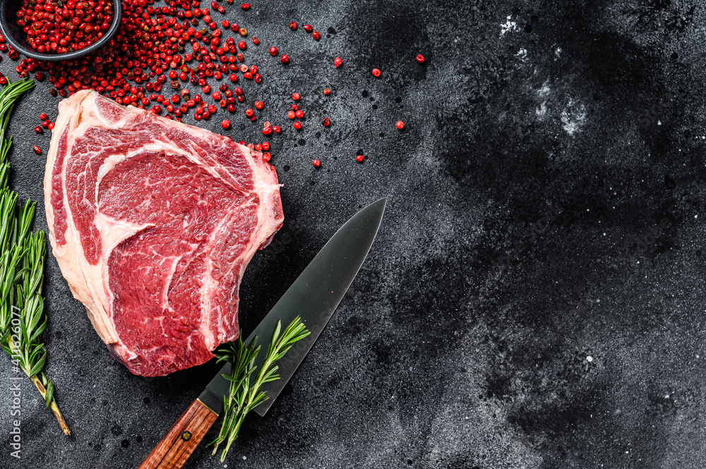Ribeye on the bone or  cowboy steak. Raw Marble beef. Black background. Top view. Copy space