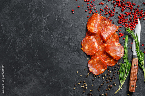 Chorizo sausage thin cut. Spanish salami with spices, paprika, pepper. Spicy food. Black background. Top view. Copy space
