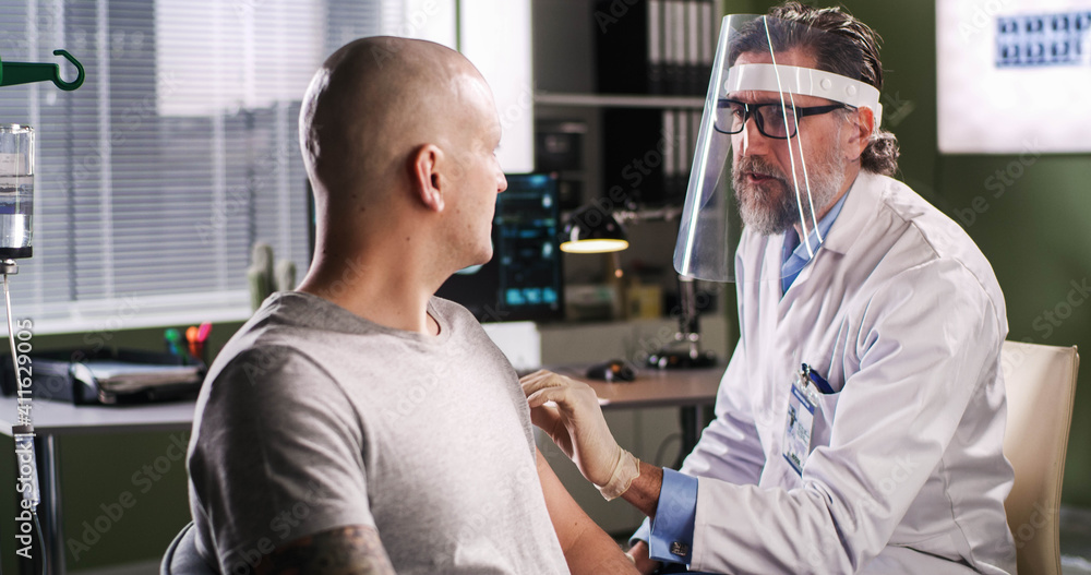 Obraz premium Bearded doctor injecting vaccine to bald patient