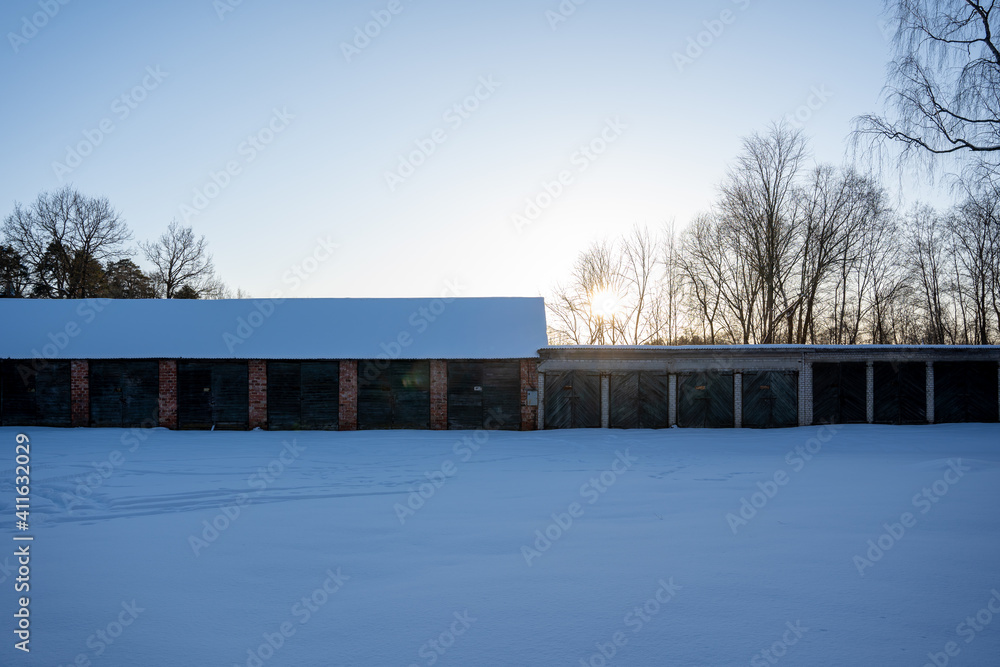 Soviet - era white brick garage complex with loose wooden debris and white snow next to them