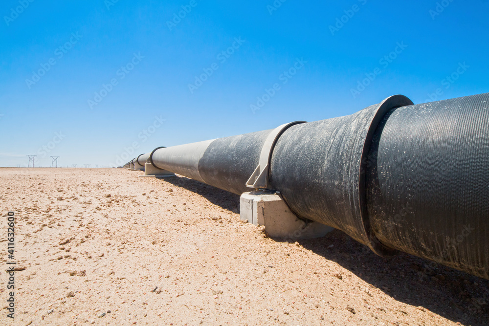 black tubes of a pipeline and power poles in the desert black tubes of a pipeline and power poles in the desert