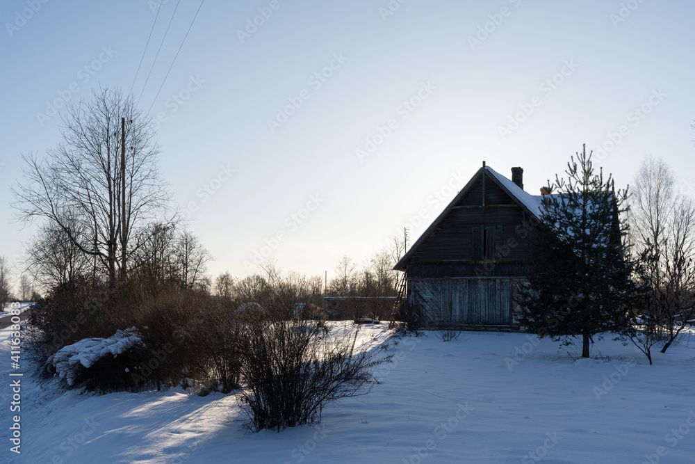 one large old wooden house stands in a white snowy meadow and looks abandoned cold and damp
