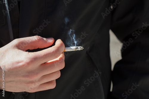 Hand of a heavy smoker with a lit cigarette, concept of tobacco addiction among young people