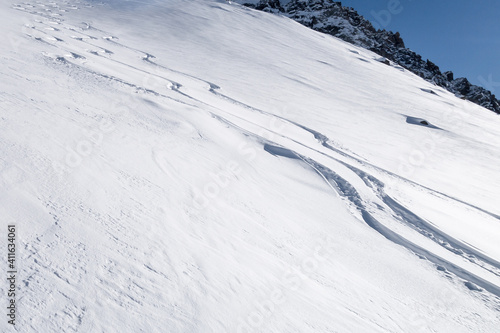 Three fresh powder snow tracks on sunny winter slope © Magnus
