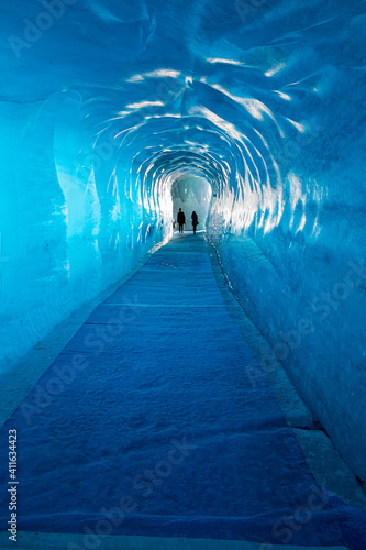 Two people silhouettes walking out of glacier tunnel photo