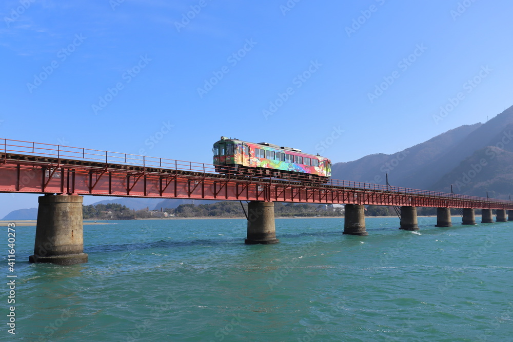 川を渡る鉄橋の上を走るカラフルな電車